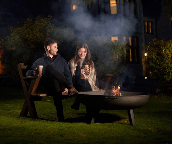 Couple Enjoying A Hot Chocolate Outside At The Firepit 