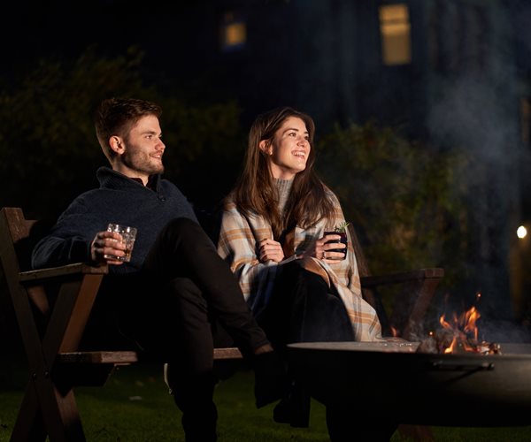 Couple Enjoying A Drink By The Outdoor Firepit 